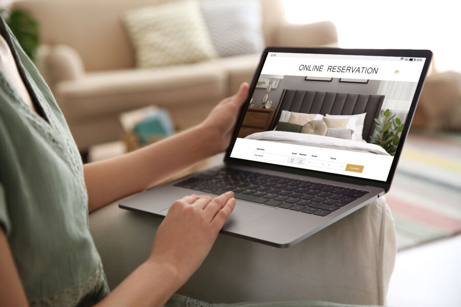 Close-up of a woman booking a hotel on her laptop while sitting at home