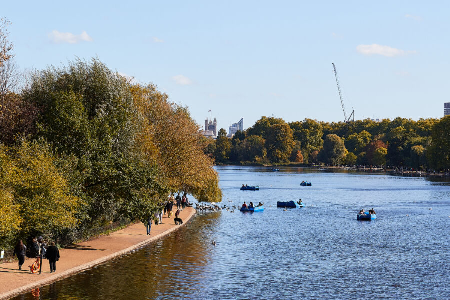 People enjoy boating and walking in Hyde Park, London, surrounded by lush greenery and scenic views