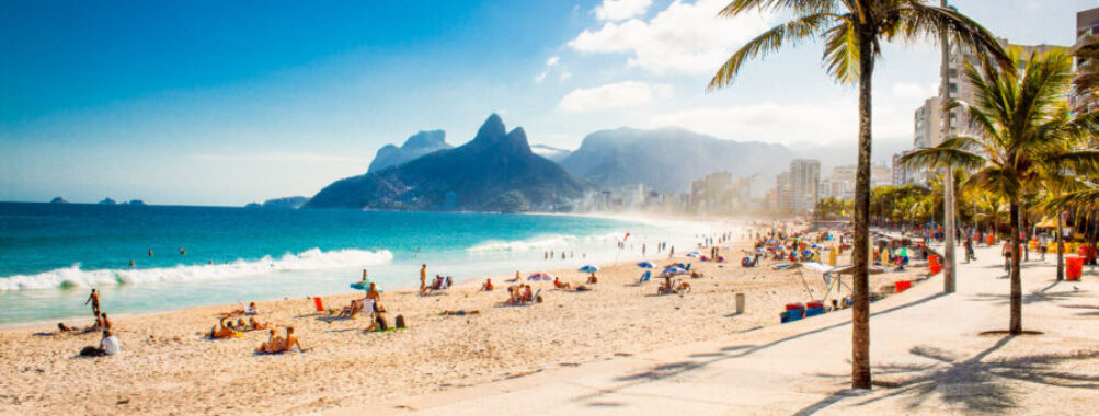 Panoramic view of Ipanema Beach featuring palm trees and the iconic Two Brothers Mountain in Rio de Janeiro, Brazil