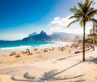 Panoramic view of Ipanema Beach featuring palm trees and the iconic Two Brothers Mountain in Rio de Janeiro, Brazil