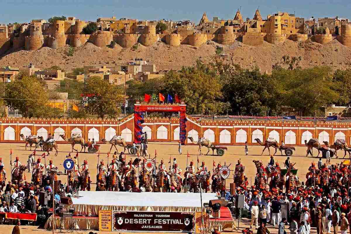 Vibrant Rajasthan Desert Festival with camels, traditional attire, and Jaisalmer Fort in the background.