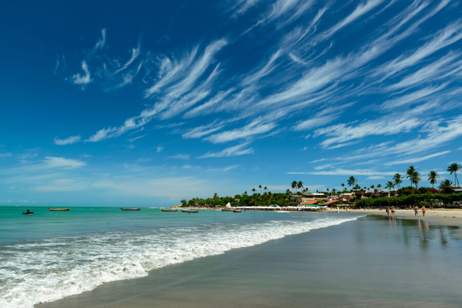 Panoramic view of Jericoacoara Beach in Brazil, showcasing a greenish sea and stunning cirrus cloud formations