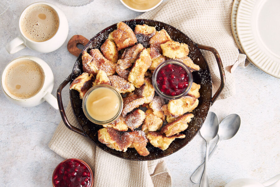 Top view of kaiserschmarrn pancakes served with cranberry jam and apple puree on a rustic wooden table