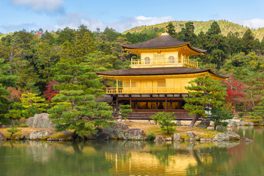 Golden Pavilion reflected in a small pond, surrounded by vibrant autumn maple trees at Kinkakuji Temple, Kyoto, Japan