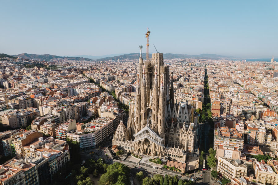 Aerial view of La Sagrada Familia Basilica in Barcelona at sunrise, showcasing the vibrant city skyline in the background