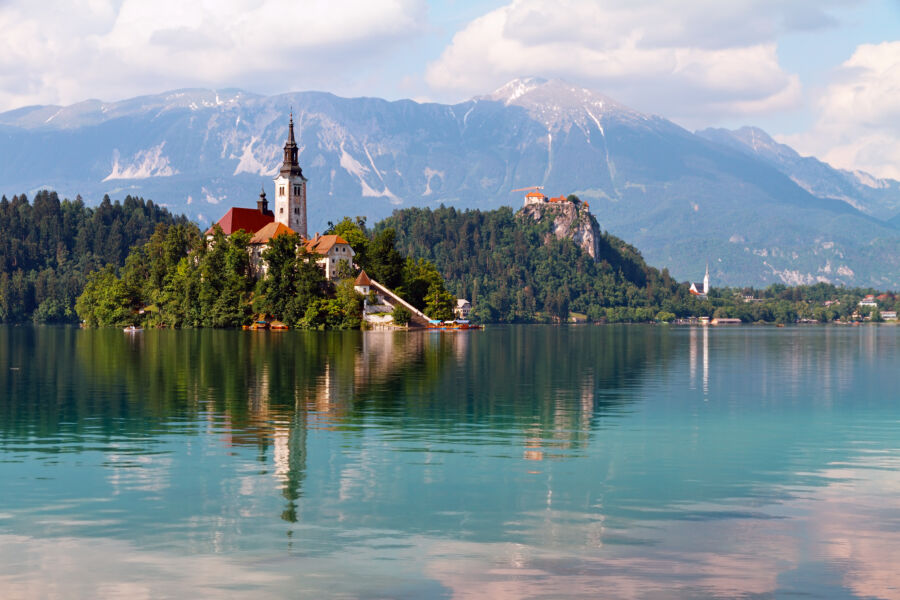 Scenic panorama of Lake Bled, featuring the iconic island church and lush mountains under a bright blue sky