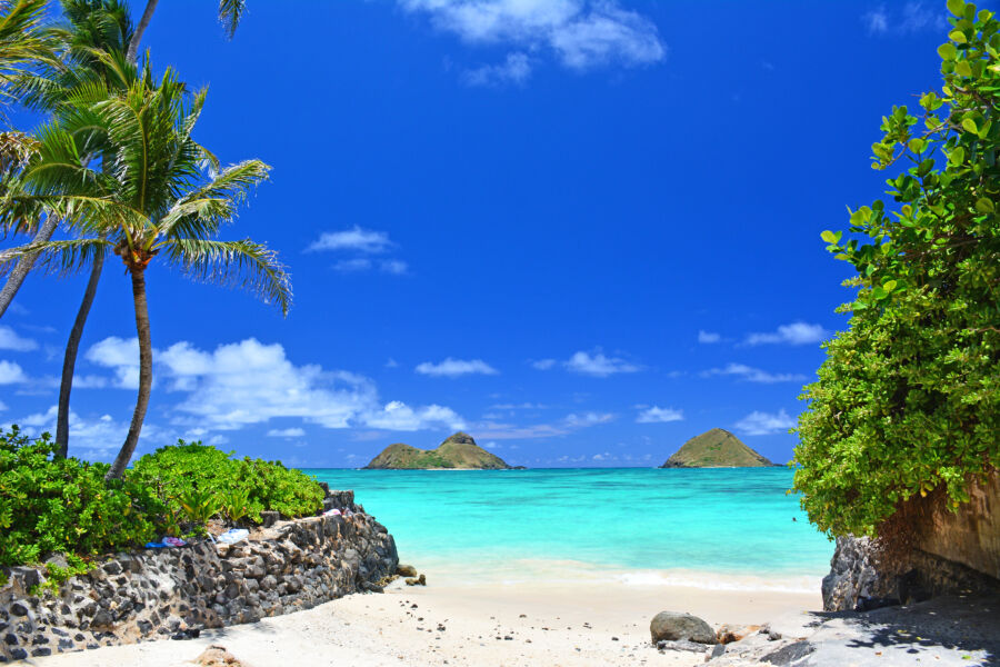 Lanikai Beach features a hidden cove with turquoise waters and the Mokes islands, illuminated by a bright sunny day in Oahu