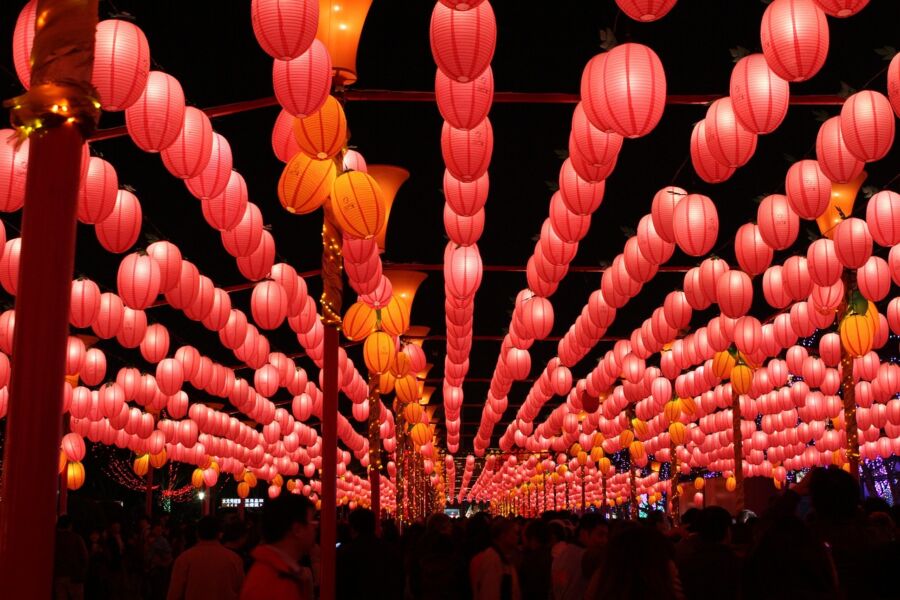 Vibrant lantern festival scene with red and yellow lanterns, festive atmosphere, and mingling crowd.