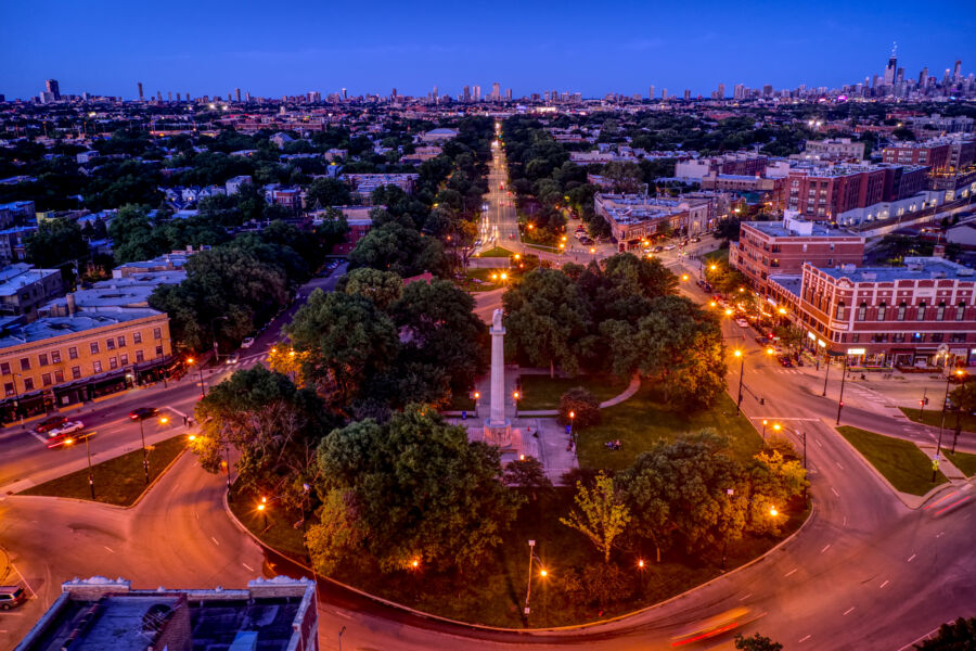 Aerial view of Logan Square in Chicago at night, showcasing illuminated streets and vibrant city life