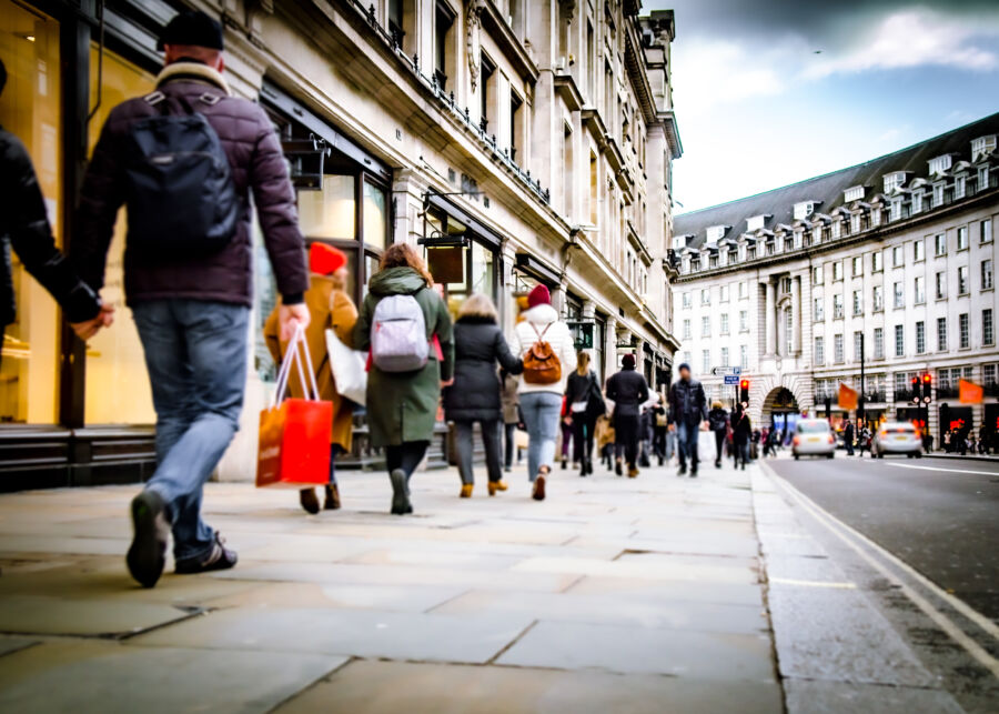 Crowds of shoppers fill a lively street in London, showcasing the vibrant atmosphere of the city's retail scene