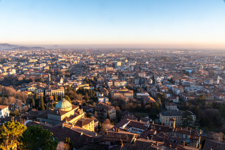 The lower city of Bergamo Bassa at sunset, featuring stunning views of Italy's architecture and a vibrant evening sky