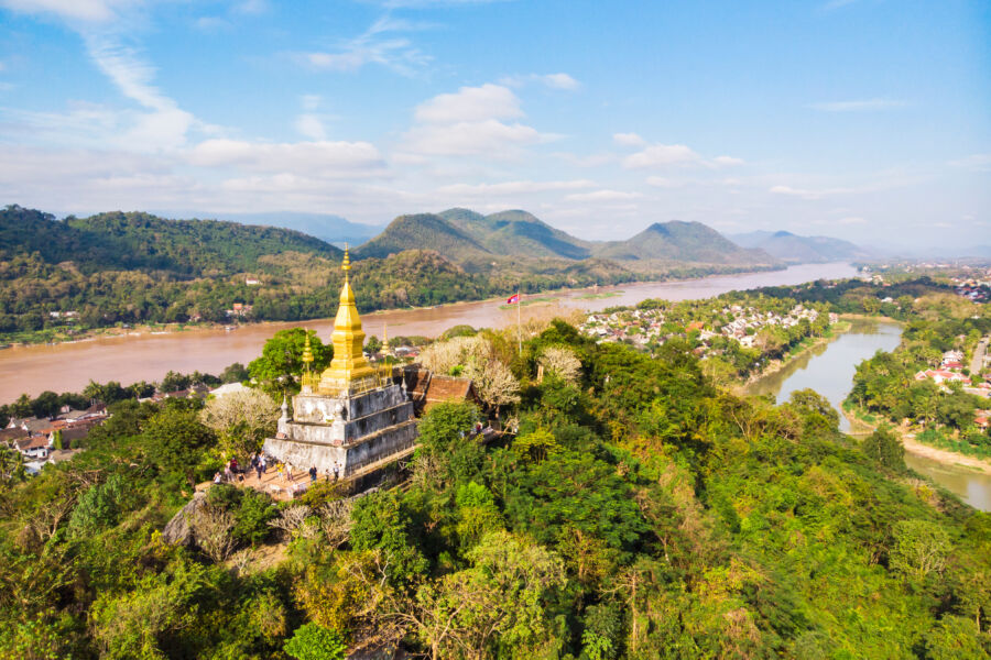 Golden pagoda of Wat Chom Si atop Mount Phou Si, overlooking the scenic landscape of Luang Prabang, Laos