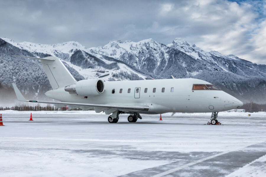 Sleek white corporate business jet sits on a snowy runway