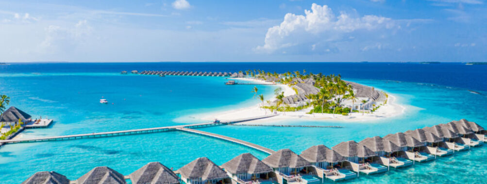 Aerial view of a luxury tropical resort in the Maldives, featuring water villas and stunning beach scenery