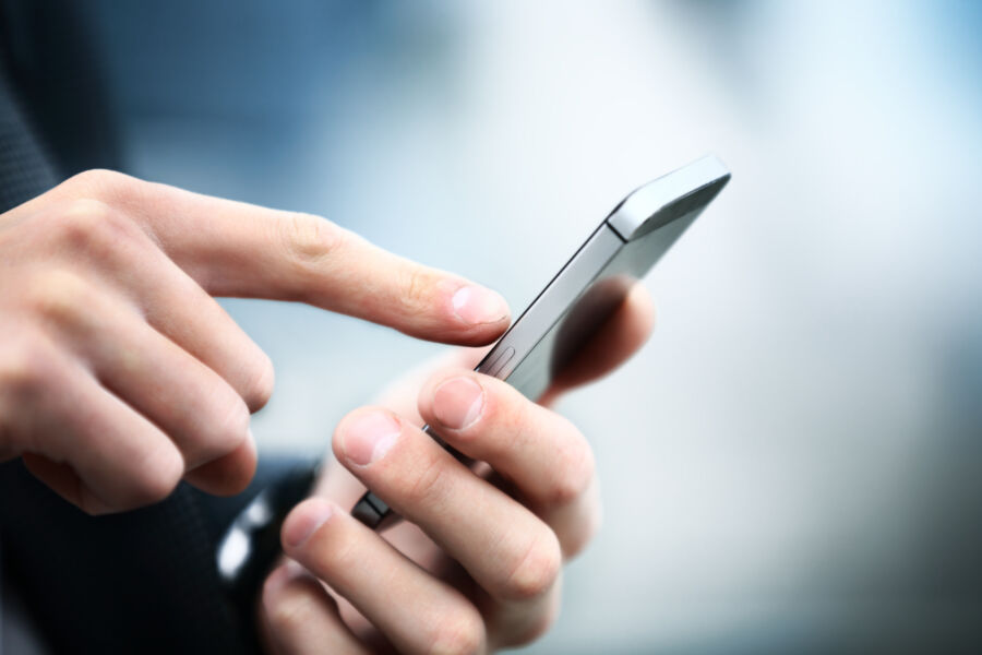 Close-up view of a man using a smartphone, concentrating on the screen with his hands positioned around the device