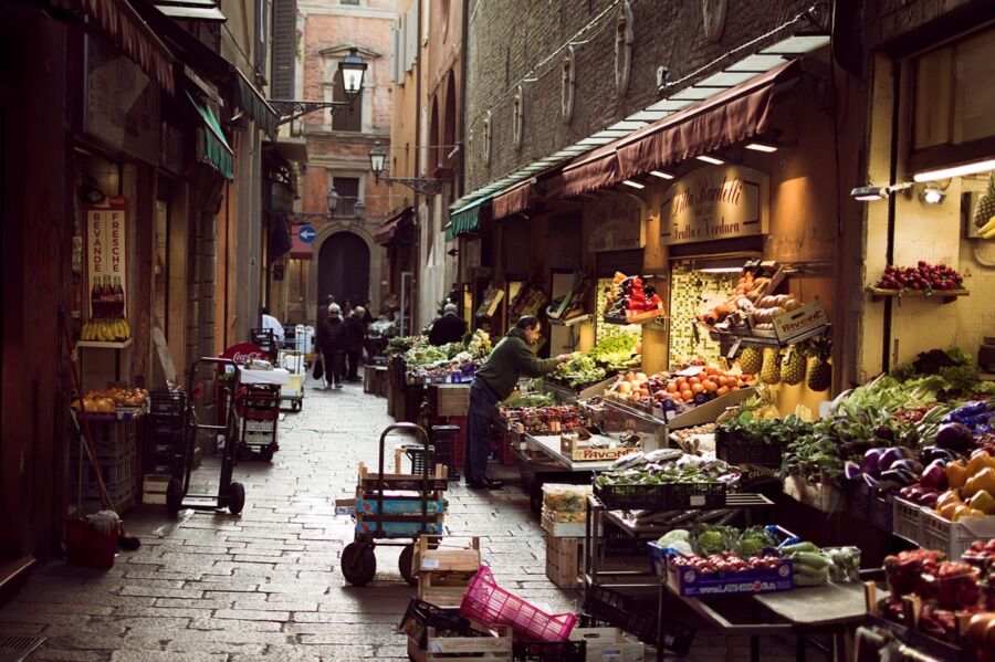 Charming European market alley with vibrant produce stalls and historic architecture.