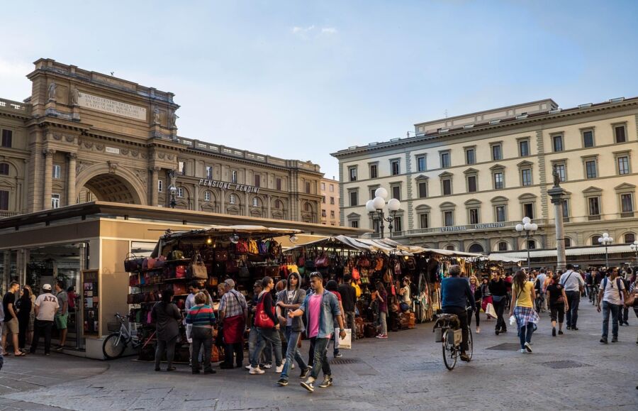 Bustling European market square with vibrant stalls and historic architecture at sunset.