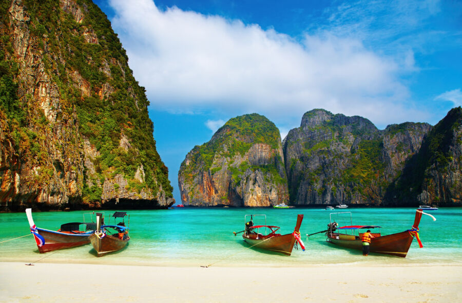 Picturesque Thai longtail boat on a serene sandy beach at Maya Bay, Thailand, with vibrant blue waters in the backgroundPicturesque Thai longtail boat on a serene sandy beach at Maya Bay, Thailand, with vibrant blue waters in the background