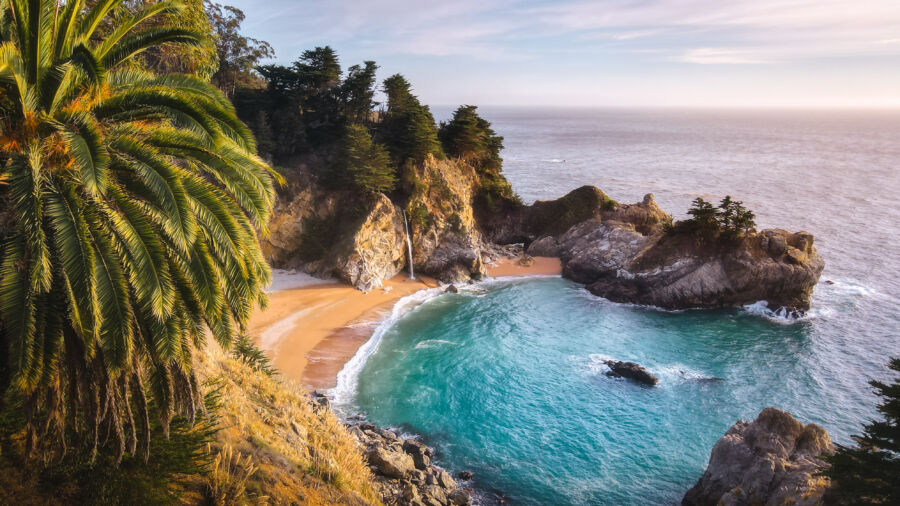 Aerial view of McWay Falls Beach in California, showcasing the stunning waterfall cascading onto the sandy shore