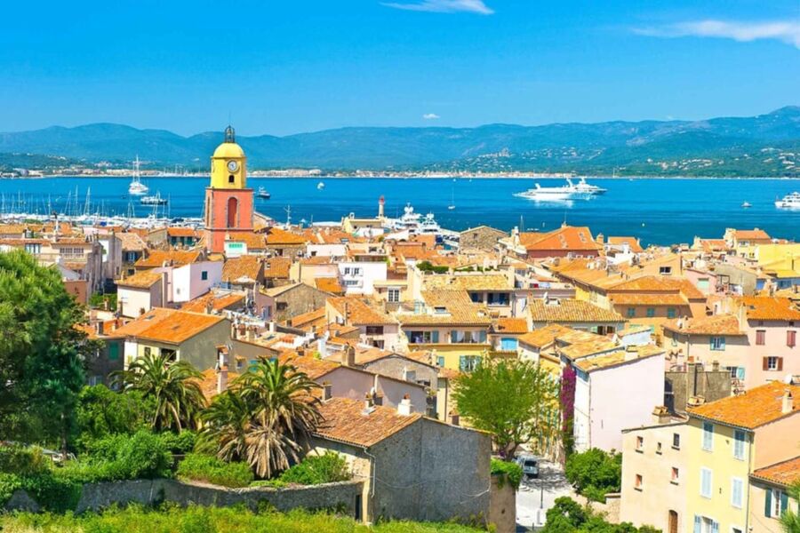 Breathtaking St. Tropez view: colorful Mediterranean town, harbor, lush hills, vibrant atmosphere.