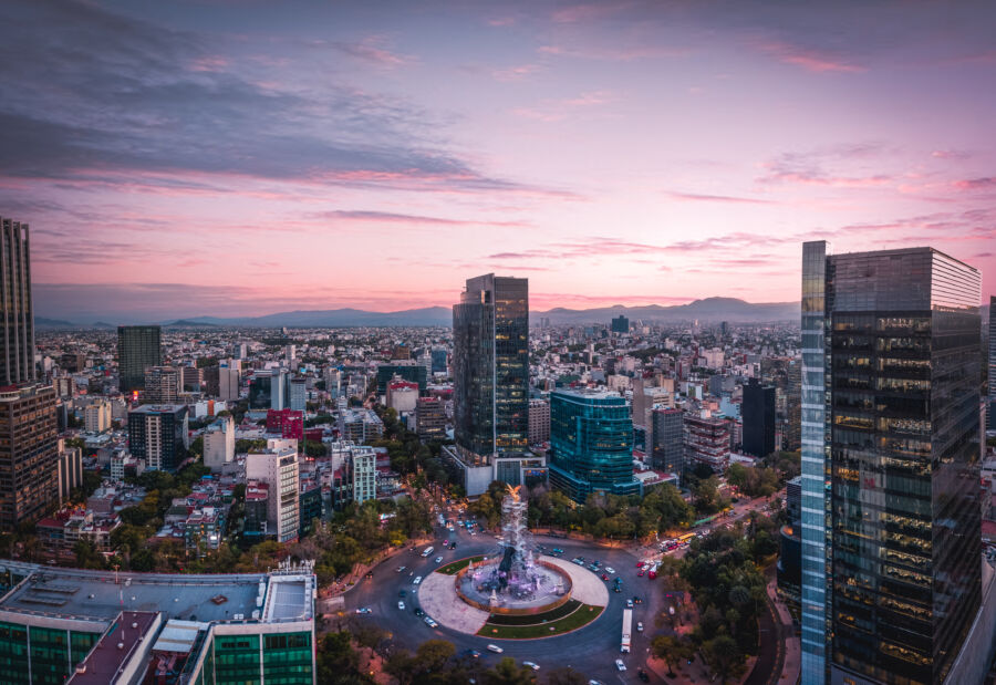 Aerial view of Reforma Street in Mexico City during sunset, showcasing vibrant colors and bustling city life