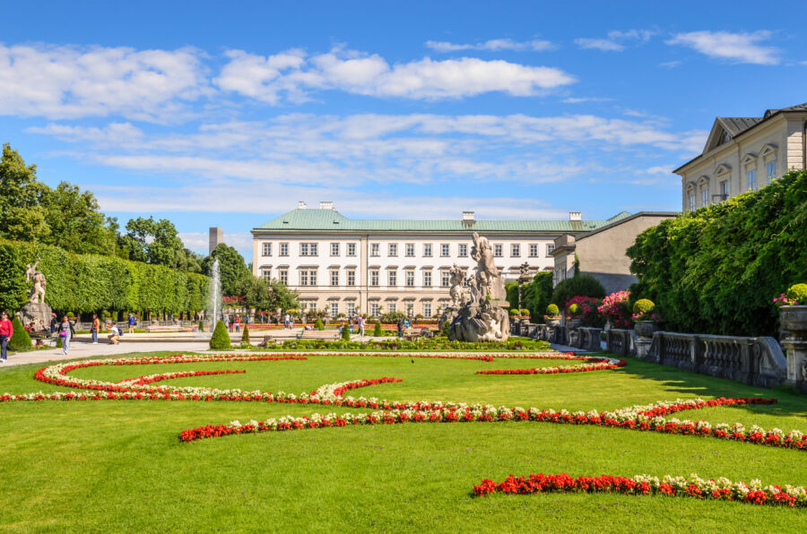 Panoramic view of Mirabell Palace and its lush gardens in Salzburg, Austria, showcasing vibrant flowers and historic architecture