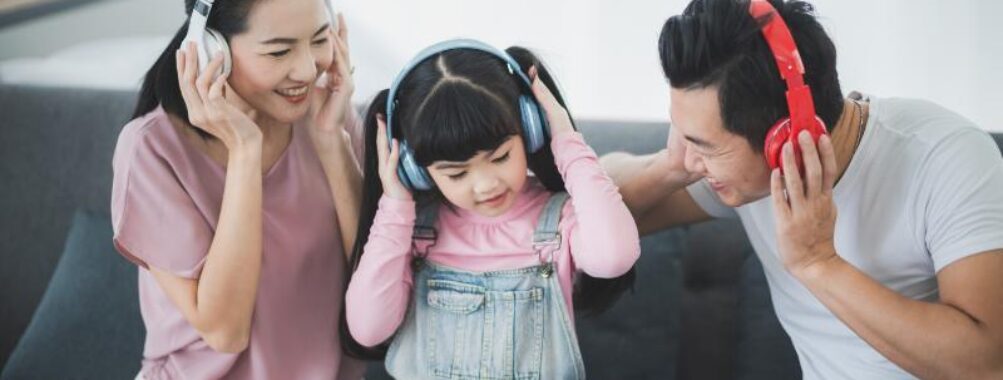 Mom and dad with female chid are listening to music with wireless headphones