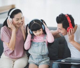 Mom and dad with female chid are listening to music with wireless headphones