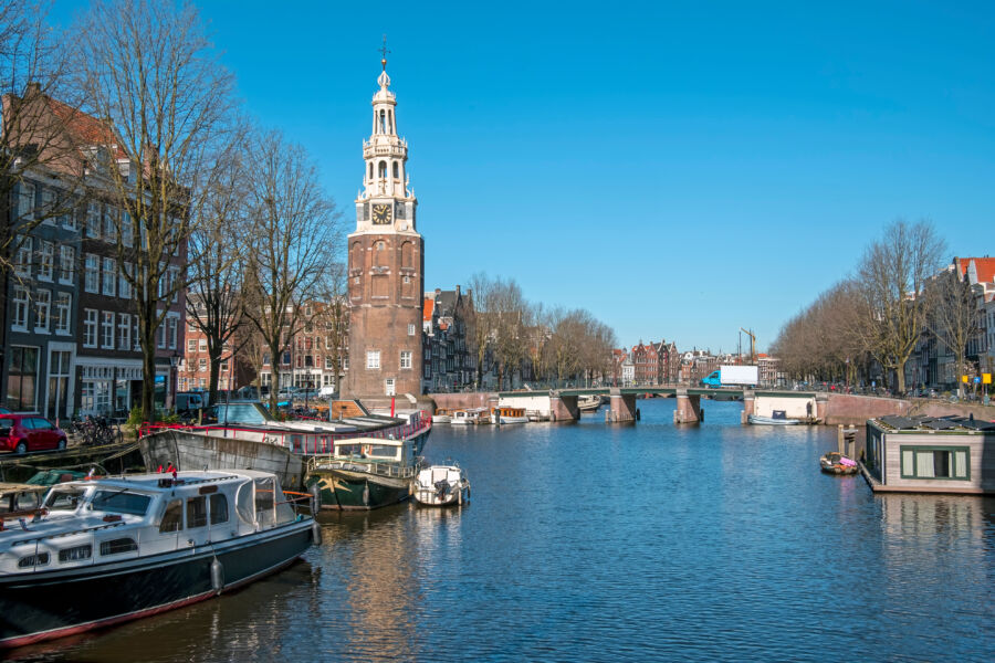 Scenic view of Amsterdam featuring the Montelbaan tower amidst traditional Dutch architecture and waterways