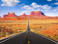 Road view in Monument Valley, Arizona, highlighting the majestic red rock formations and vast desert scenery