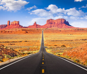 Road view in Monument Valley, Arizona, highlighting the majestic red rock formations and vast desert scenery