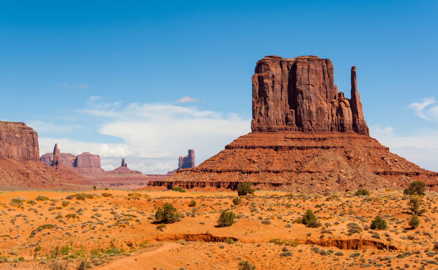 Panoramic view of Monument Valley, Arizona, featuring striking rock formations against a vibrant blue sky