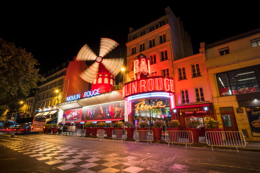 Night view of the Moulin Rouge cabaret exterior in Paris, glowing with lights