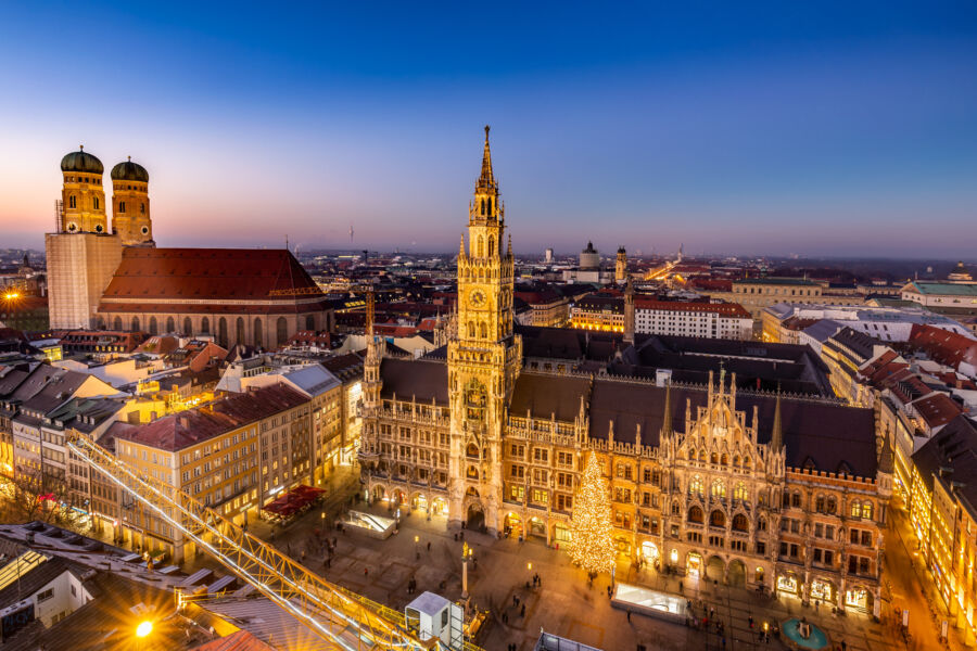 Night view of Munich's old town, showcasing illuminated buildings and vibrant street lights against a dark sky