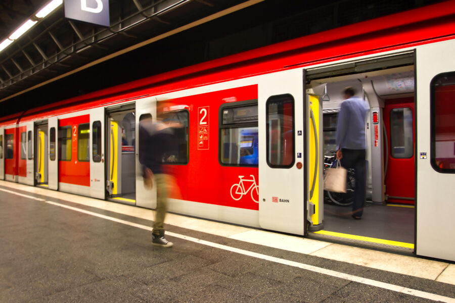 Munich subway station with passengers on the platform and train door wide open in the background