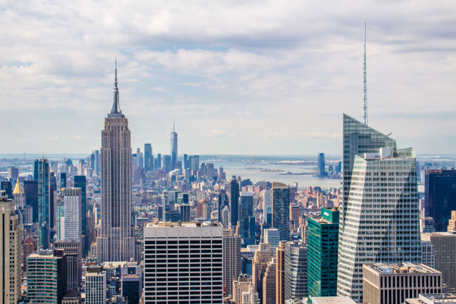 The New York City skyline showcases towering skyscrapers under a bright blue sky