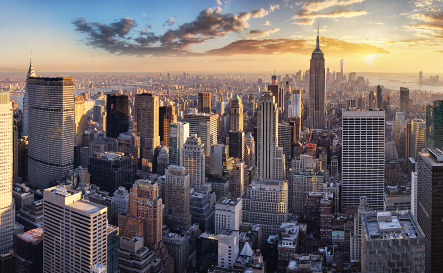 The skyline of New York City silhouetted against a stunning sunset, with a sky painted in warm colors of dusk