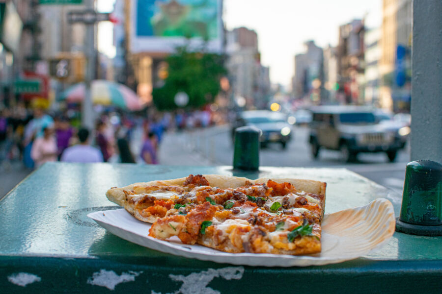 Single slice of pizza sits on Canal Street, embodying the iconic food culture of New York City