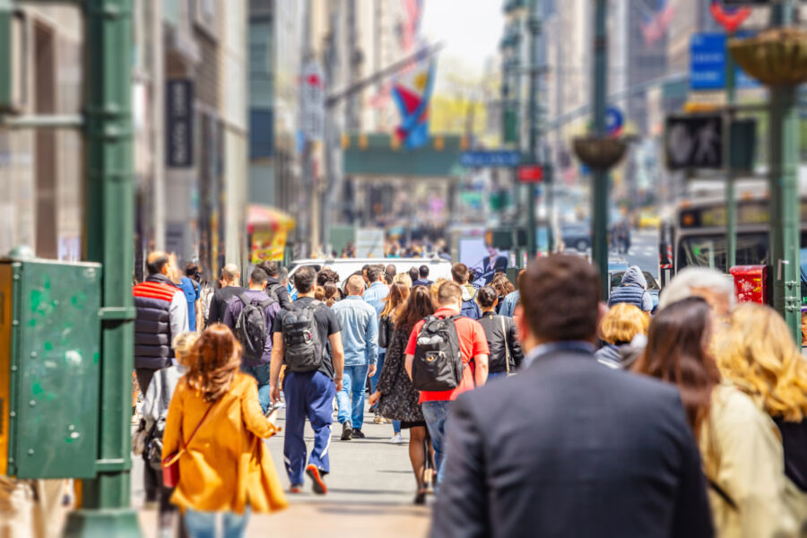 Bustling New York street scene featuring tall buildings and a diverse crowd of pedestrians navigating the urban landscape