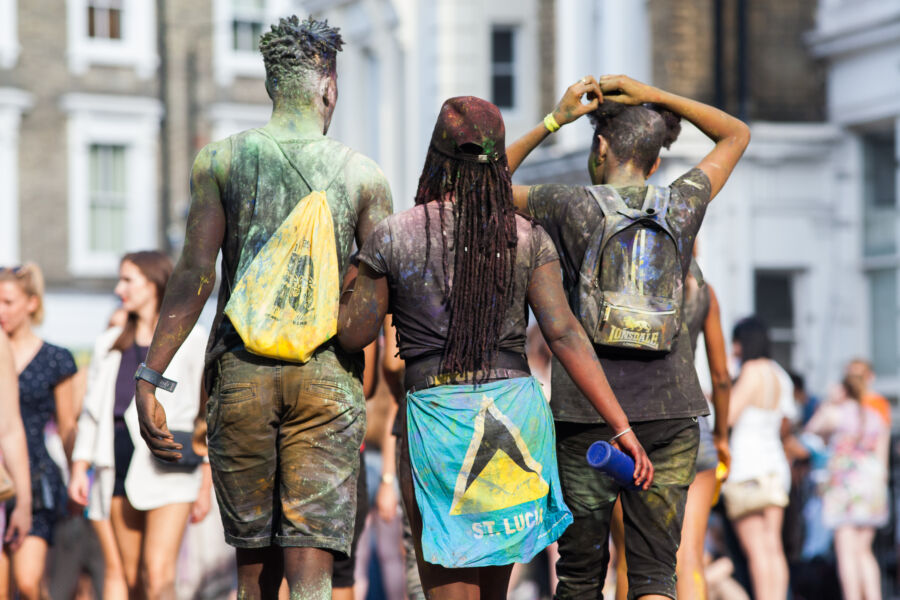 Lively scene of unidentified people in bright costumes participating in the Notting Hill Carnival in London, showcasing joy and culture