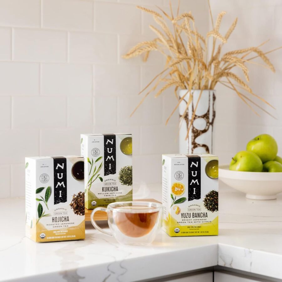 Modern kitchen featuring Numi organic Japanese teas with glass cup, dried wheat, and green apples.