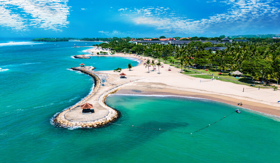 Aerial view of Nusa Dua beach in Bali, showcasing its turquoise waters and sandy shores under a clear blue sky