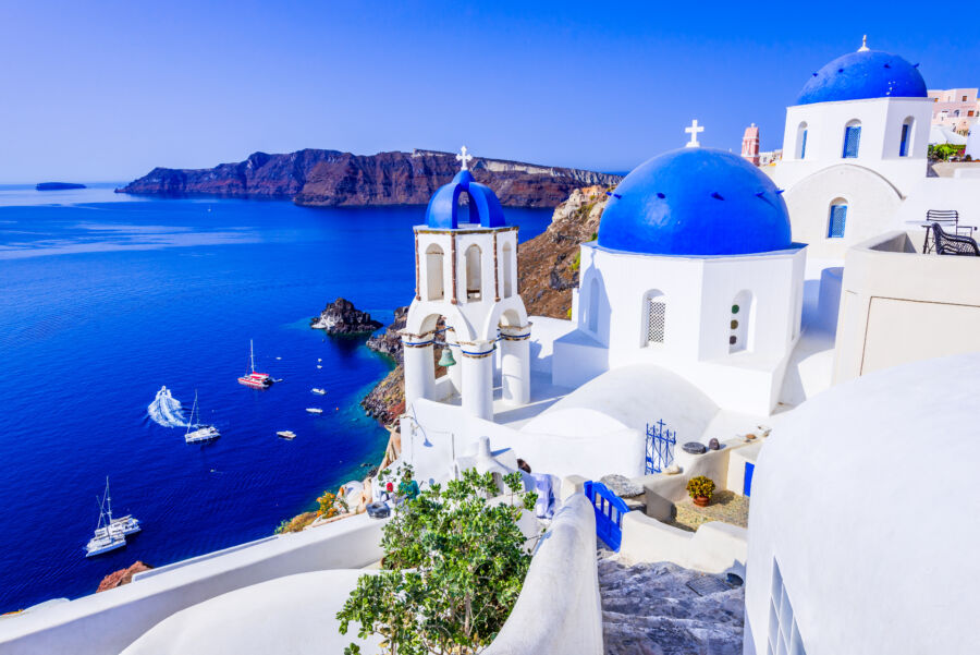 Picturesque view of Oia, Santorini, featuring a blue-domed church overlooking the stunning caldera