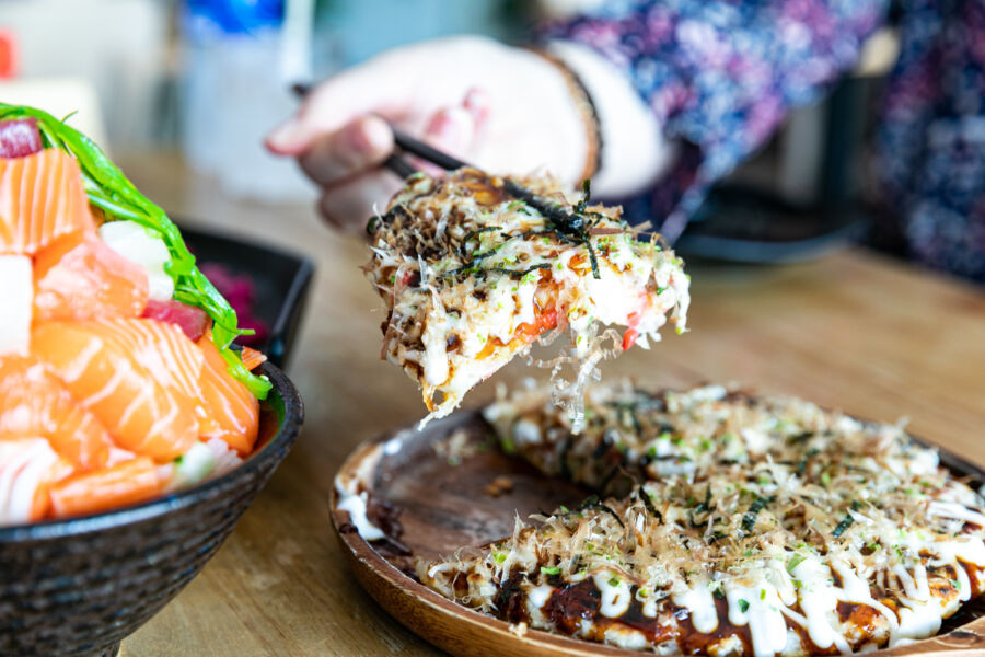 Japanese okonomiyaki, resembling pizza, displayed on a table, showcasing its vibrant toppings