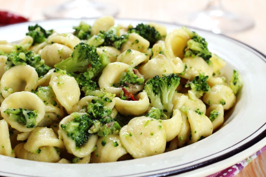 Close-up of orecchiette pasta with vibrant broccoli rabe, showcasing their textures and colors in a delicious arrangement