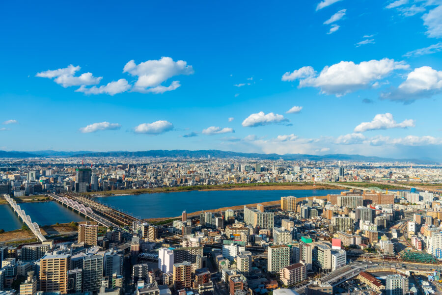 Sunset over Osaka's Umeda district skyline, with the Yodo River reflecting the vibrant colors of the evening sky