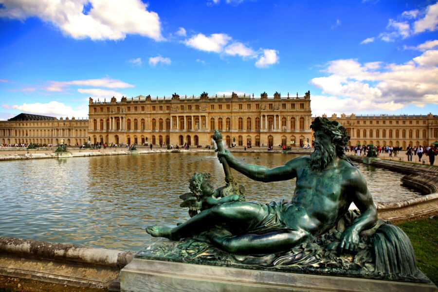 The magnificent Palace of Versailles in France, surrounded by beautiful gardens and a striking sculpture