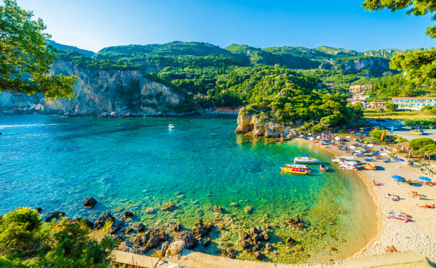 Scenic view of a serene beach and a boat in the turquoise waters of Paleokastritsa, located on Corfu island, Greece