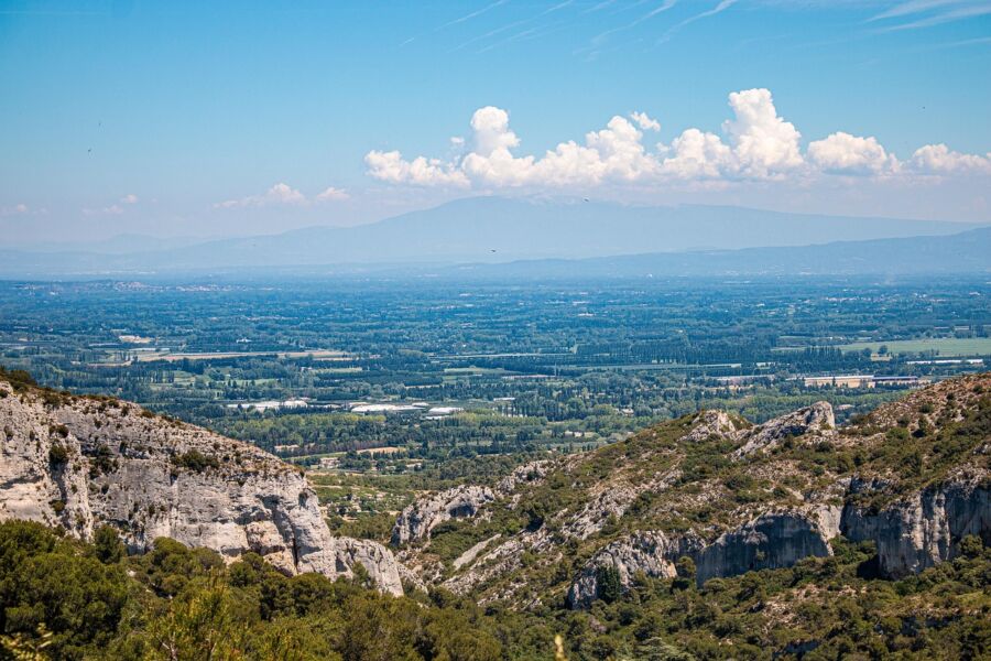 Panoramic view of lush landscape with rolling hills, cliffs, fields, and distant mountains.