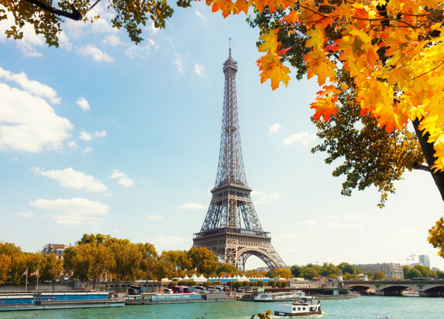 Aerial view of the Eiffel Tower over the Seine River, framed by autumn trees in Paris, France